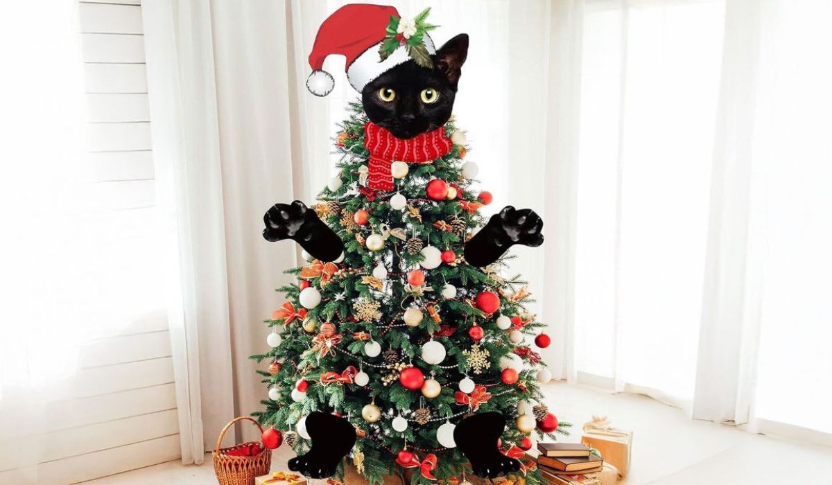 A black cat stands atop a decorated Christmas tree, surrounded by colorful ornaments and twinkling lights.